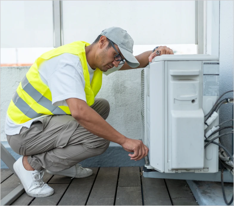 Worker adjusting air conditioner on rooftop